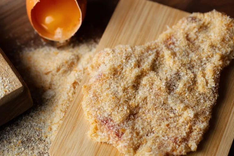Raw Wiener Schnitzel, breaded steak, egg on wooden background