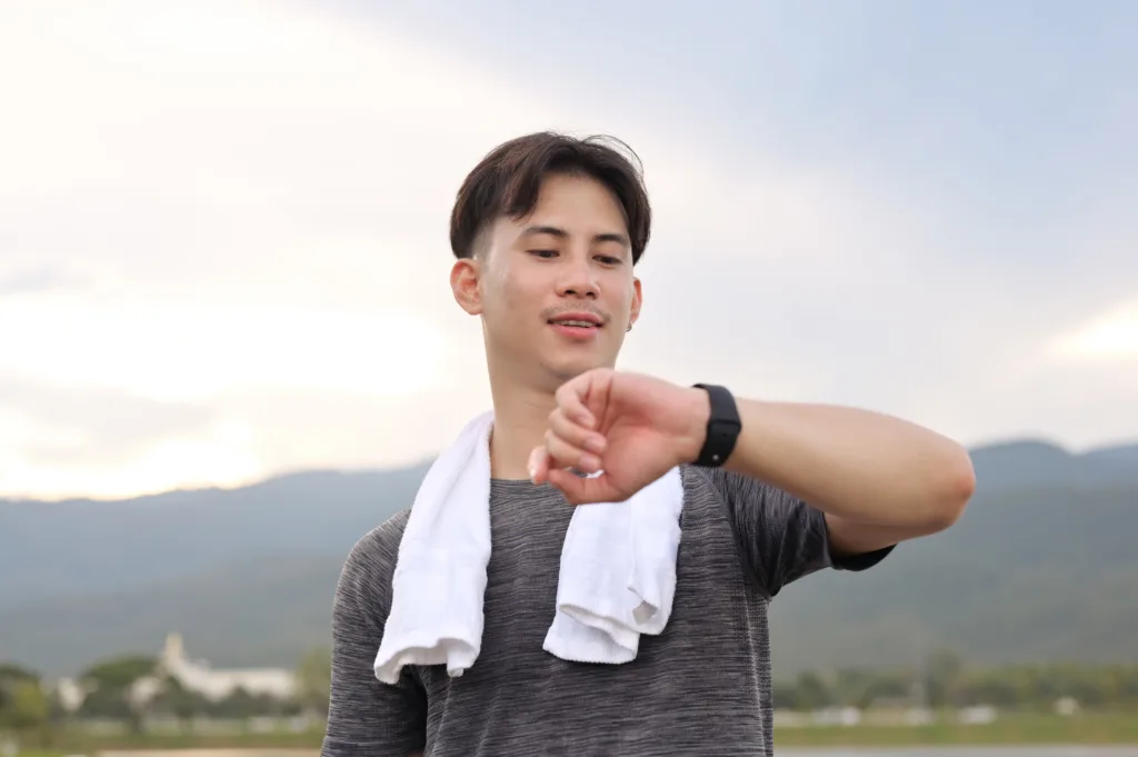 Smiling athlete checking fitness tracker after outdoor workout. Healthy lifestyle concept.