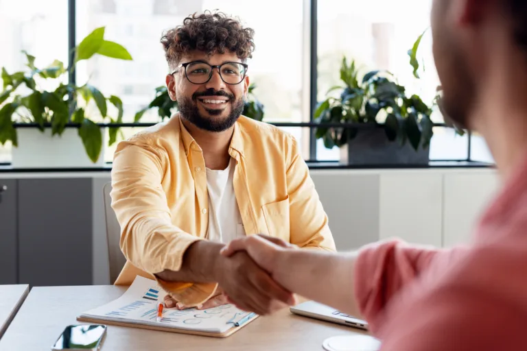 Smiling businessmen reaching a consensus and shaking hands in a modern professional office setting