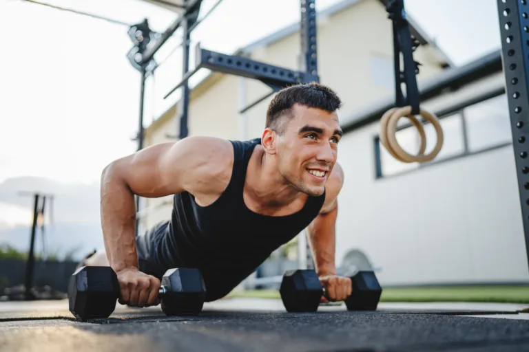Sportsman doing dumbbell push up during workout outdoor