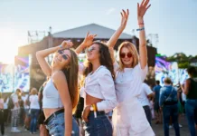 To je 5 evropskih festivalov, ki jih morate obiskati vsaj enkrat v življenju Sunlight illuminates the happy crowd, friends celebrate, party atmosphere by the ocean. Group of young women enjoying at a beach music festival, dancing together in summer outfits with sunglasses.