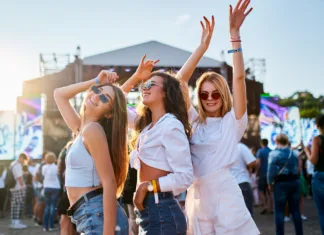 To je 5 evropskih festivalov, ki jih morate obiskati vsaj enkrat v življenju Sunlight illuminates the happy crowd, friends celebrate, party atmosphere by the ocean. Group of young women enjoying at a beach music festival, dancing together in summer outfits with sunglasses.