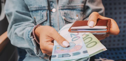 The girl takes euro banknotes out of her wallet. The concept of devaluation and inflation of the European currency