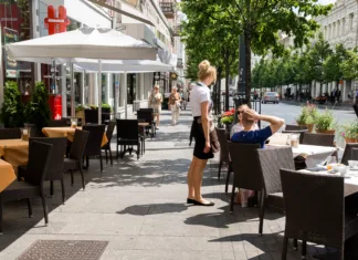 Največja napaka študentov pri poletnem delu na prostem Vilnius, Lithuania - July 01, 2015 - Outdoor cafe scene with female waitress and male customer on a sunny urban street.