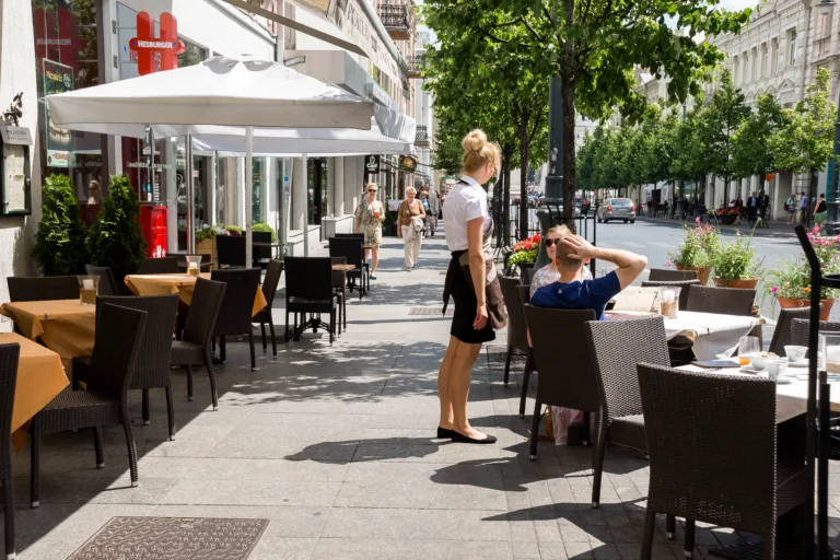 Vilnius, Lithuania - July 01, 2015 - Outdoor cafe scene with female waitress and male customer on a sunny urban street.