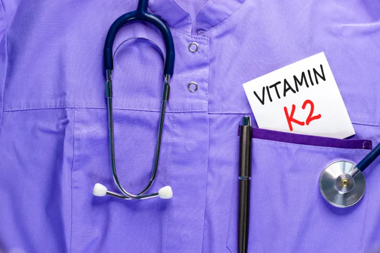 Vitamin K2 phylloquinone symbol. Concept words Vitamin K2 on beautiful white card. Stethoscope and pen. Beautiful medical uniform. Medical healthy lifestyle Vitamin K2 phylloquinone concept.