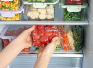 Kako pravilno shranjevati hrano v hladilniku, zamrzovalniku in shrambi Woman taking plastic bag with frozen tomatoes from refrigerator, closeup
