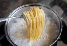 Skoraj vsi vodo za testenine solijo ob napačnem času: glavni kuhar največjega proizvajalca testenin na svetu razkriva, kdaj je pravi trenutek Yellow noodles or spaghetti cooking in boiling water pot with indoor low lighting.