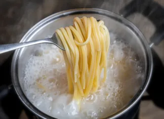 Skoraj vsi vodo za testenine solijo ob napačnem času: glavni kuhar največjega proizvajalca testenin na svetu razkriva, kdaj je pravi trenutek Yellow noodles or spaghetti cooking in boiling water pot with indoor low lighting.
