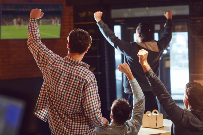 Young people watching football on TV in the bar. Fans in the pub.