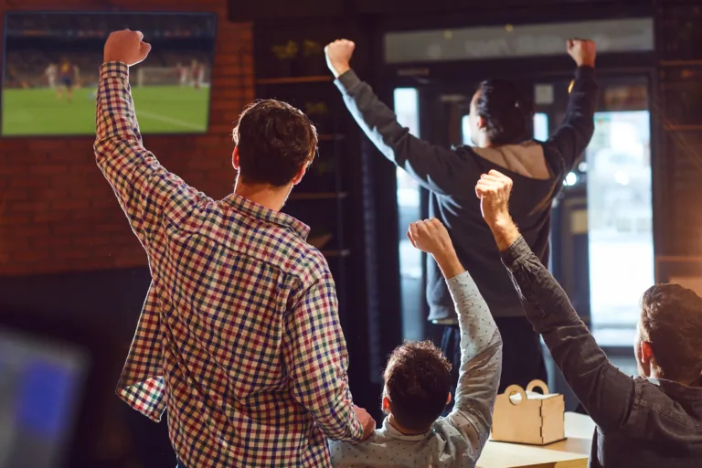 Young people watching football on TV in the bar. Fans in the pub.