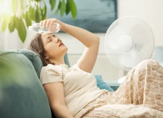 To so najboljši skriti kotički Ljubljane za pobeg pred poletno vročino Young woman sitting on the couch at home and keeping a fresh water bottle on her forehead, she is suffering from the heat