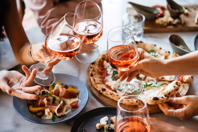 friends-enjoy-a-dinner-party-with-pizza-and-rose-wine-in-a-bar-or-a-restaurant-stockpack-istock Friends enjoy a dinner party with pizza and rose wine in a bar or a restaurant.