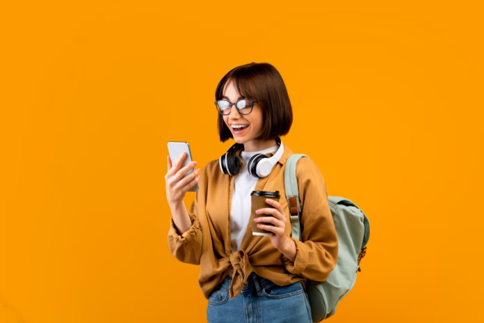 happy-female-student-with-backpack-headphones-smartphone-and-takeaway-coffee-standing-over-yellow-studio-background-young-lady-ready-for-classes-chatting-on-cellphone-stockpack-istock Happy female student with backpack, headphones, smartphone and takeaway coffee standing over yellow studio background. Young lady ready for classes, chatting on cellphone