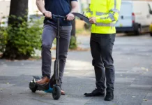 E-skiroji pod drobnogledom: močno se zaostrujejo pravila – to morate vedeti Officer Holding Clipboard In Hand Standing With Man Riding Electric Scooter On City Street
