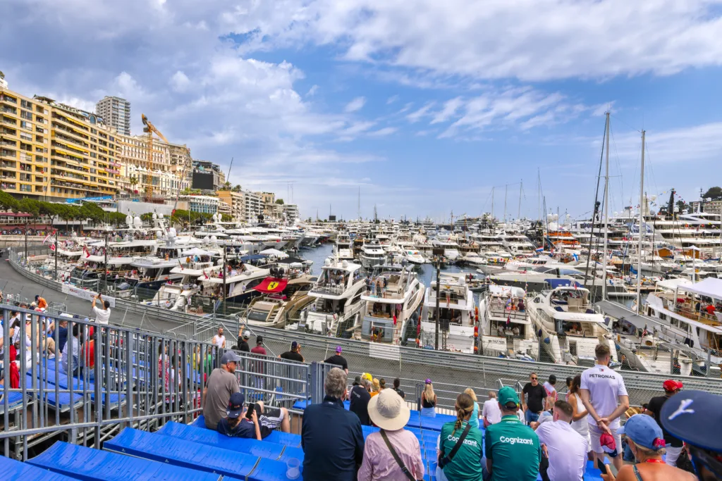 Visitors enjoy the trackside view from the stands at Tribune K of the Formula 1 grand prix track and luxury yachts in the harbor on the Monaco Grand Prix race day.