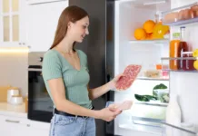 Številni salamo v hladilniku shranjujejo narobe: Tako lahko hitreje izgubi okus in svežino Woman with ham and salami near open refrigerator in kitchen
