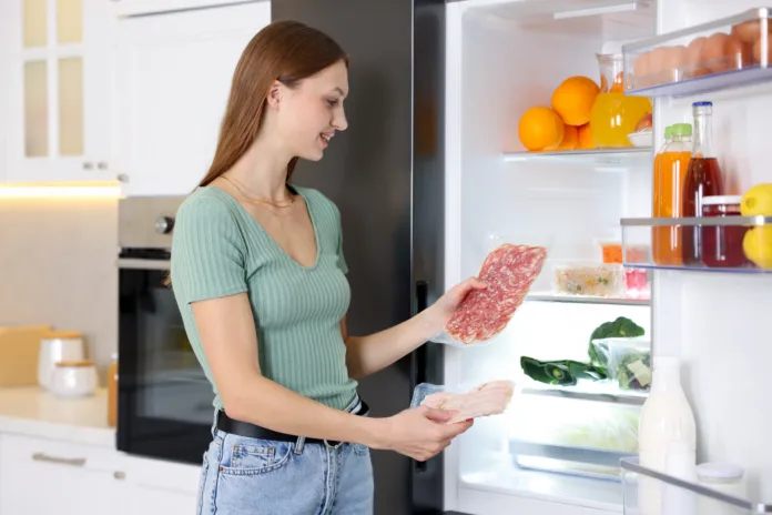woman-with-ham-and-salami-near-open-refrigerator-in-kitchen-stockpack-istock Woman with ham and salami near open refrigerator in kitchen