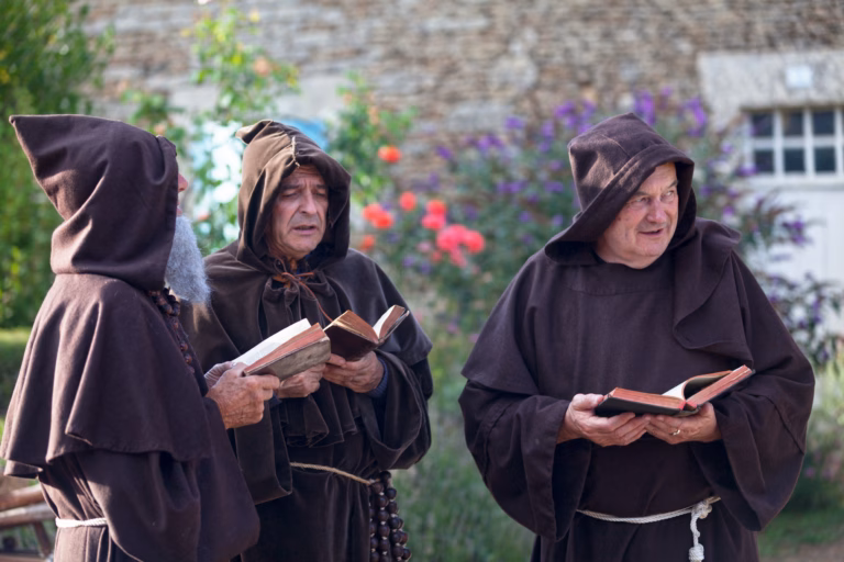 Bazoges-en-Pareds, France - July 29 2017: Three medieval monks singing in choir during the annual "Nocturnes Médiévales" festival. In summer, in many medieval towns in France, festivals are held where people can disguise in knights, monks, farmers"u2026 of the medieval period.