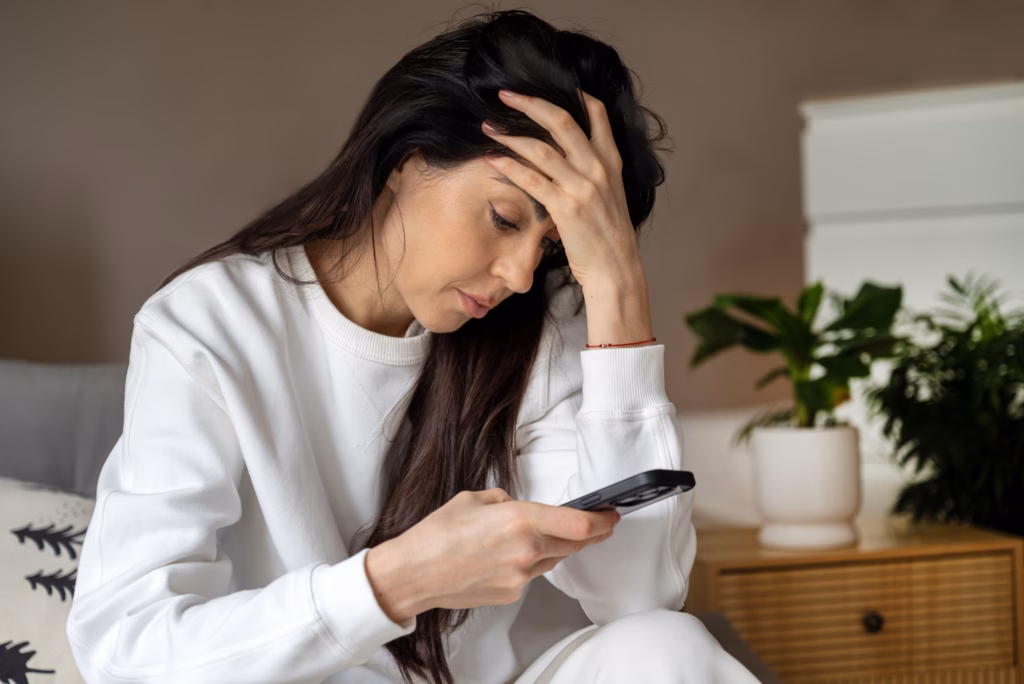 Beautiful Sad Young woman looking her smartphone at home