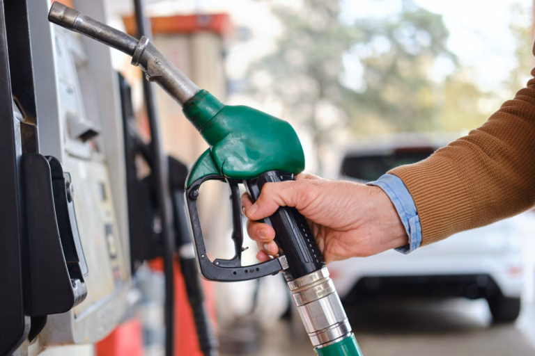Close-up of a hand holding a green fuel pump nozzle, refueling a car at a gas station in barcelona