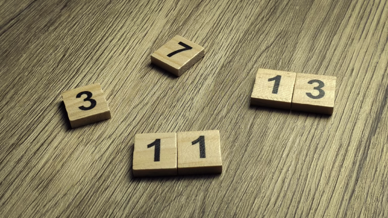 Collection of prime number wooden tiles scattered on a wooden table for mathematics and education concept