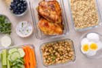 Glass containers with quinoa, chickpeas, eggs, and fresh vegetables ready for meal prepping