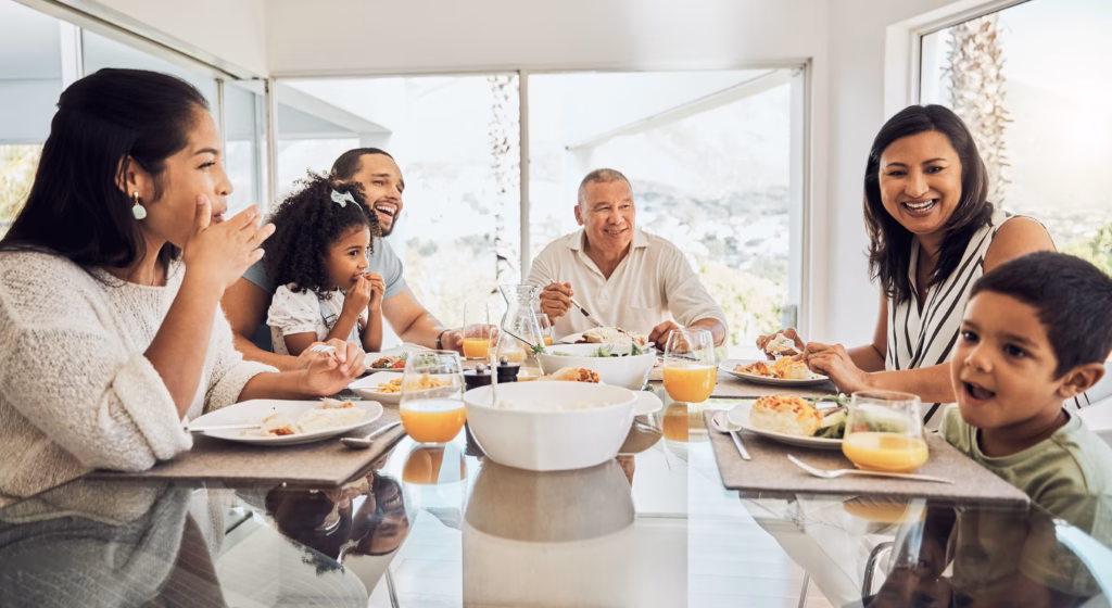Happy, food and big family morning breakfast at dining table in home talking, eating and bonding. Grandparents, parents and children relaxing while enjoying meal together with happiness, love and fun