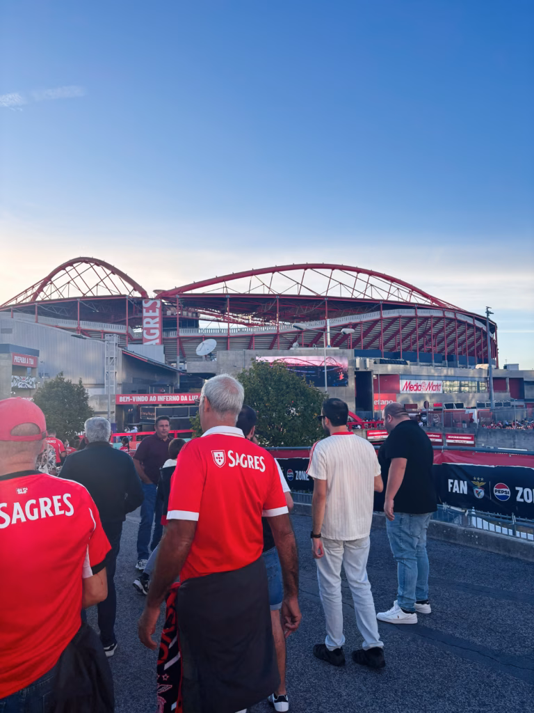 Lisbon, Portugal - September 28, 2025: Crowd of fans in red Sagres shirts near a modern Estádio da Luz stadium in Lisbon , Portugal, during a sunny outdoor event.