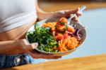 Shot of fitness woman eating a healthy poke bowl in the kitchen at home.