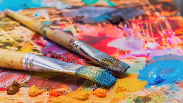 Used brushes on an artist's palette of colorful oil paint for drawing and painting