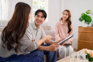 Professional Asian salesperson meets clients at home discussing important financial agreements insurance planning providing expert advice