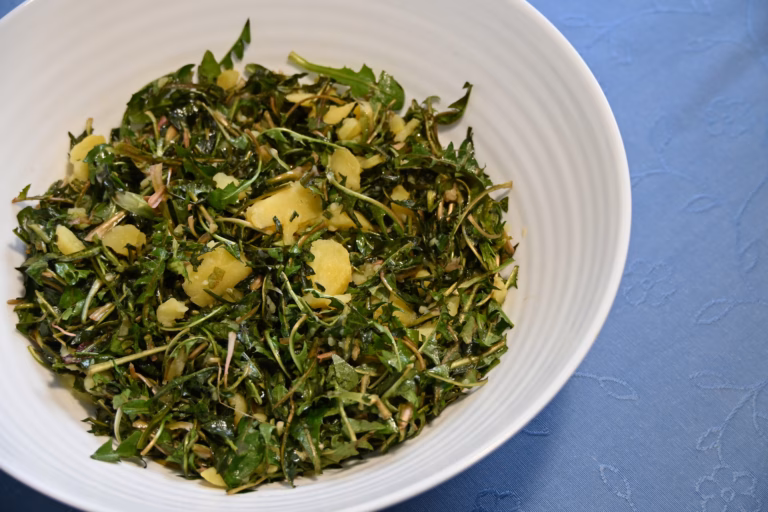 Dandelion salad with warm potatoes served on the table.