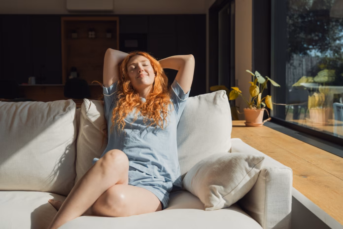 young-adult-woman-with-red-hair-relaxing-comfortably-on-a-modern-couch-at-home-stretching-enjoying-sunlight-through-the-window-promoting-well-being-and-a-peaceful-lifestyle-stockpack-istock Young adult woman with red hair relaxing comfortably on a modern couch at home, stretching enjoying sunlight through the window, promoting well-being and a peaceful lifestyle